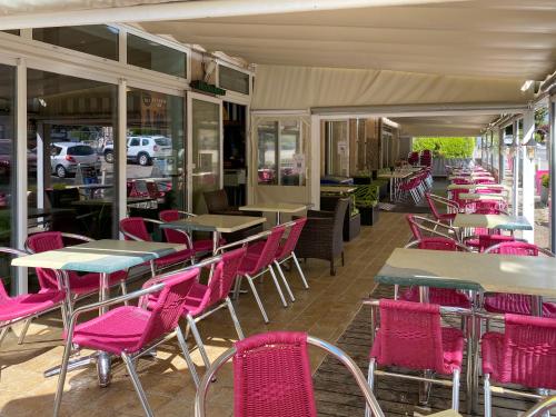 una fila de mesas y sillas en un restaurante en Hôtel Les Tilleuls de Pareloup à Salles-Curan, en Salles-Curan