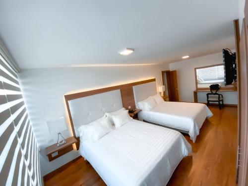 a bedroom with two beds and a television at Hotel Miraflores in Ambato