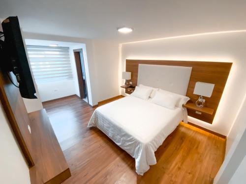 a bedroom with a white bed and wooden floors at Hotel Miraflores in Ambato