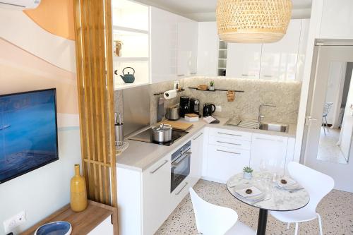 een keuken met witte kasten en een tafel en stoelen bij Elégant appartement moderne - Cure et vacances in Balaruc-les-Bains