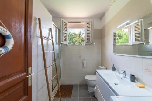 a bathroom with a sink and a toilet and windows at Villa Ti'Kemy avec piscine au sel in Le Lamentin