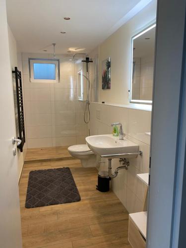 ein Badezimmer mit einem Waschbecken, einem WC und einem Spiegel in der Unterkunft Moderne Ferienwohnung mit Retro-Charme in Wülfrath