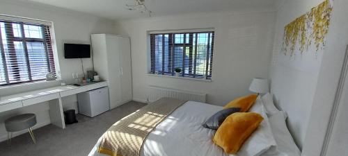 a bedroom with a bed and a desk and windows at Barn Farm Guest House in Cold Norton