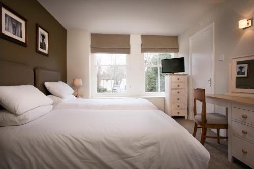 a bedroom with two beds and a desk and a television at The Millers Arms Inn in Canterbury