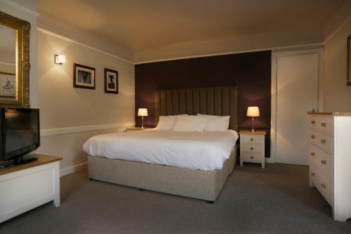 a bedroom with a large bed and a television at The Millers Arms Inn in Canterbury