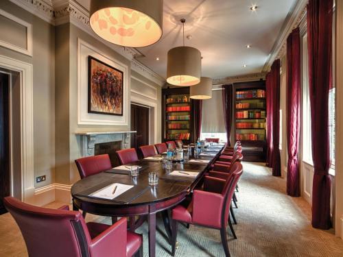a long dining room with a long table and red chairs at Bedford Lodge Hotel & Spa in Newmarket