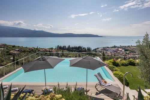 a swimming pool with two umbrellas and a view of the water at Villa Agave exclusive pool in Toscolano Maderno