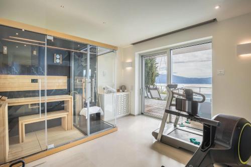 a gym with a treadmill and a glass wall at Villa Agave exclusive pool in Toscolano Maderno