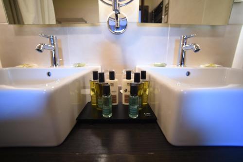uma casa de banho com dois lavatórios e duas garrafas de água em Hôtel Les Rives em Guebwiller