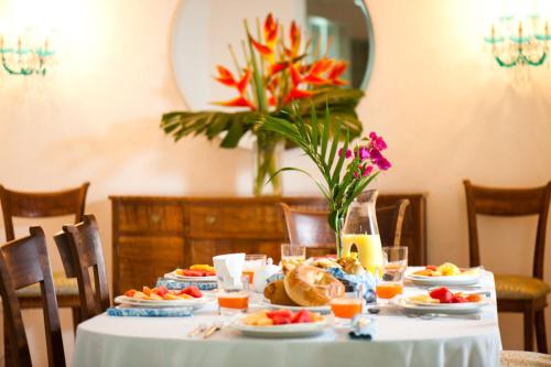 Una mesa con platos de comida y un jarrón con flores. en Hotel Aguamarina Boutique, en Cartagena de Indias