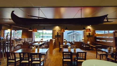 a restaurant with tables and chairs and a large boat hanging from the ceiling at Hotel Guossi in Karigasniemi