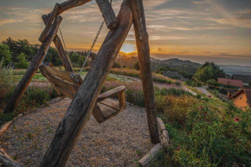 a wooden swing on a hill with a sunset in the background at Country House Zunko in Jelovec