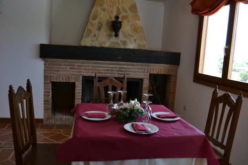 a table with a red table cloth and a fireplace at Hotel Rural Ibipozo in El Almicerán