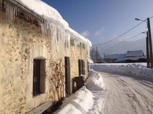 un edificio cubierto de nieve con carámbanos. en Ferme de la grande Moucherolle, en Villard-de-Lans