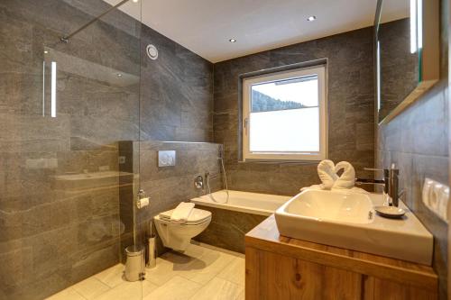 a bathroom with a sink toilet and a window at Chalet Bella in Pettneu am Arlberg