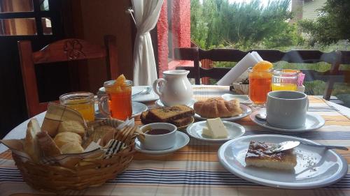 uma mesa com pequeno-almoço de pão e sumo de laranja em Hosteria Rukahué em El Calafate