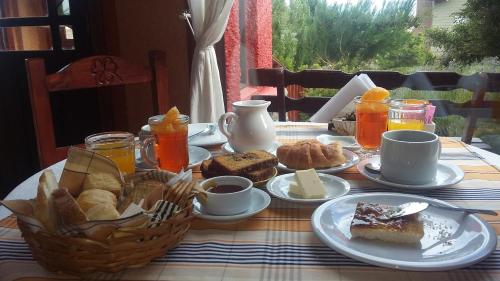 a table with a breakfast of bread and orange juice at Hosteria Rukahué in El Calafate