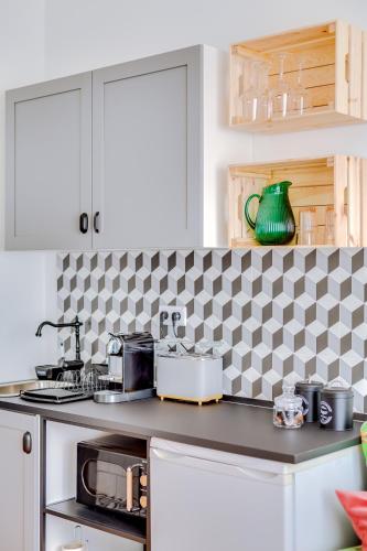 a kitchen with white cabinets and a black and white checkered wall at À da Avó -The Guesthouse in Faro