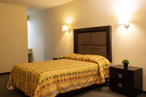 a hotel room with a bed with a yellow bedspread at BONITTO INN® Gonzalez in Gonzalez