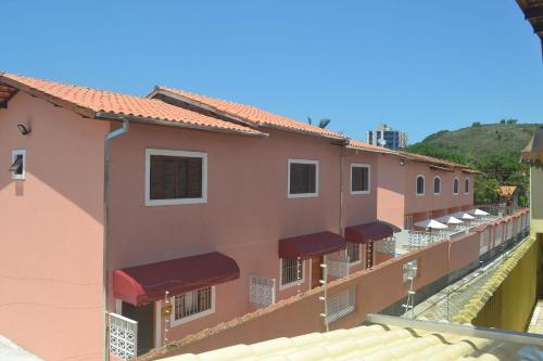 eine Reihe rosafarbener Gebäude mit roten Markisen in der Unterkunft Chalés por temporada no Villagio Santa Mônica, em Caraguatatuba in Caraguatatuba