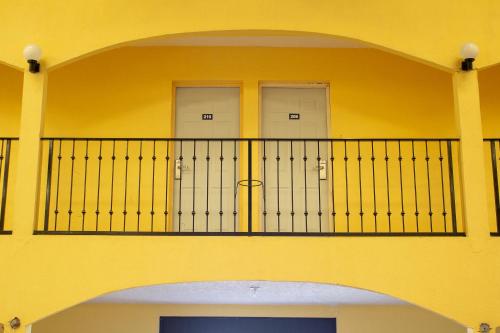 a yellow building with a balcony with two doors at BONITTO INN® Gonzalez in Gonzalez