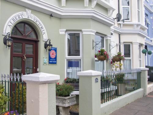 una casa blanca con una puerta y una valla en Albert & Victoria Guest House en Eastbourne