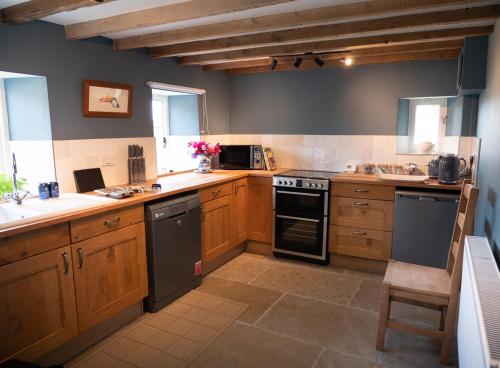 a kitchen with wooden cabinets and a stove top oven at Drovers Cottage in Belsay