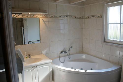 a bathroom with a tub and a sink at Ferienhaus-Kinderlieb in Baabe