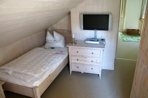 a bedroom with a bed and a tv and a dresser at Ferienhaus-Kinderlieb in Baabe