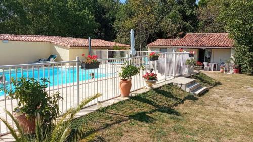 a white fence next to a swimming pool with plants at Les Deux Riviéres in Les Touches-de-Périgny