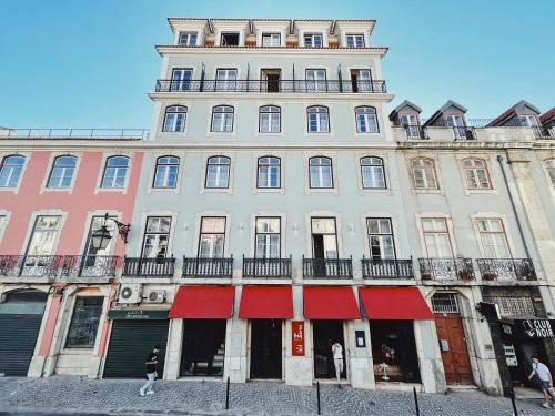 a large white building with red awnings on it at Esqina Cosmopolitan Lodge in Lisbon