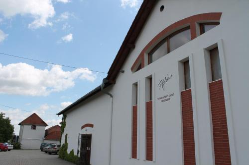 a white building with windows on the side of it at Tiffán's Pincészet és Panzió in Villány