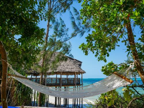 a beach area with a beach umbrella and palm trees at Z-Lodge Zanzibar in Kiwengwa