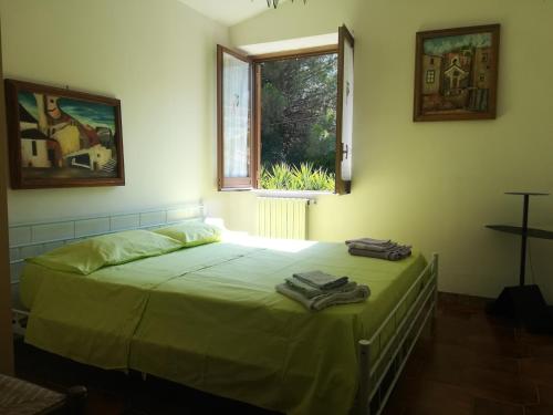 a bedroom with a bed with green sheets and a window at Casa Giordano Holidays in Tramonti
