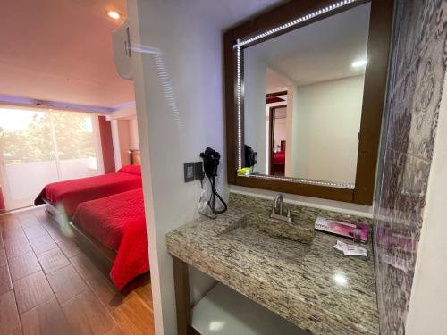 a bathroom with a sink and a mirror and a bed at La Mansión del Faro in Tecolutla