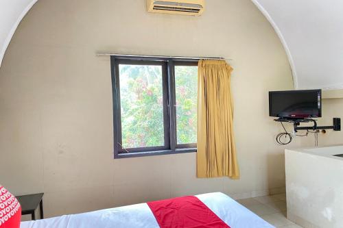 スバンにあるSUPER OYO Flagship 90644 Cottage Nalendra Nuansa Nusantaraの窓、ベッド、テレビが備わるベッドルーム1室が備わります。