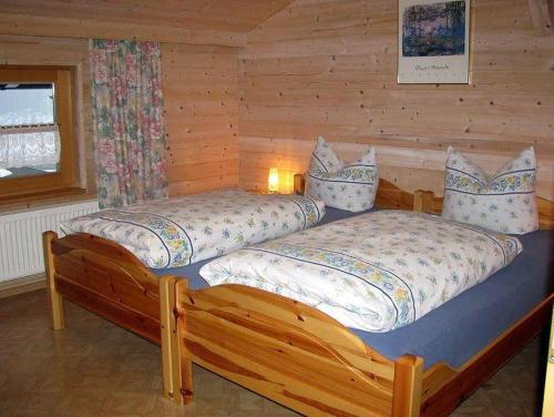 two beds in a log cabin bedroom with a window at Haus-Spannbauer-Wohnung-Dreisessel in Altreichenau
