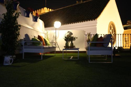 a patio with two chairs and a table on the grass at Hostal Santa Catalina in Seville