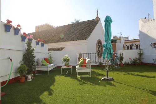 a backyard with a lawn with chairs and an umbrella at Hostal Santa Catalina in Seville