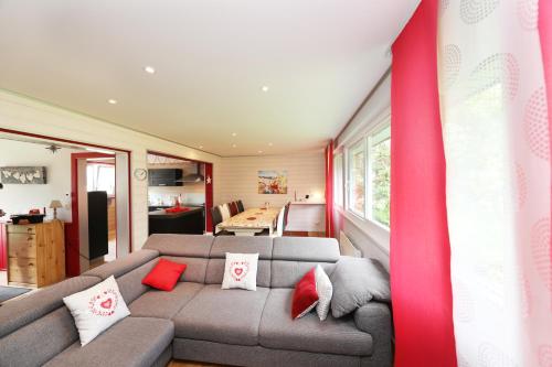 a living room with a gray couch and red pillows at Chalet en Couleurs in Xonrupt-Longemer
