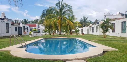 a swimming pool in the middle of a yard with houses at Casa de las Palmas in Zihuatanejo