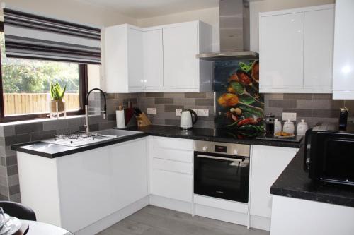 una cocina con armarios blancos y un aparato negro en City Centre Town House with Riverside Views and Free Parking 1BAK, en York