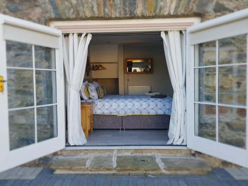 1 dormitorio con 1 cama y 2 ventanas en Magical 3-Bed Stone Built Cottage - Sleeps 6, en Ballynahinch