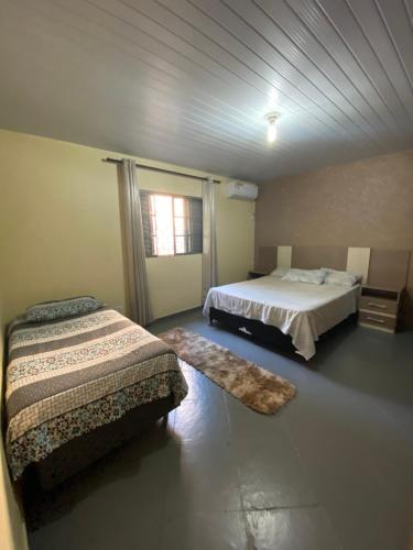 een slaapkamer met 2 bedden en een raam bij Casa Grande com 2 quartos e 1 suíte in Foz do Iguaçu