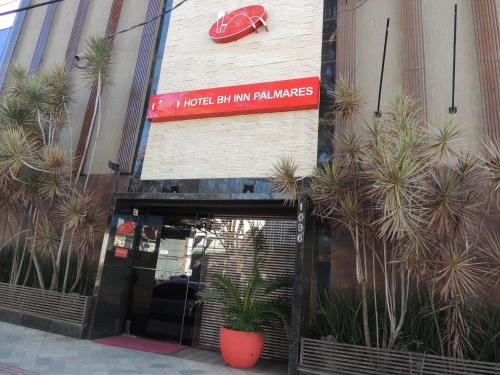 uma entrada de loja com palmeiras em frente em Hotel BH Inn Palmares - By UP Hotel - Acesso Cristiano Machado em Belo Horizonte