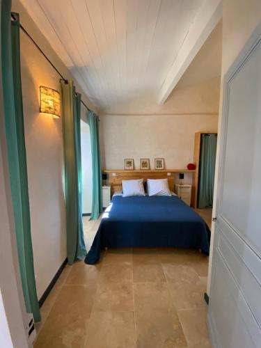 a bedroom with a blue bed and green curtains at Petite maison Peyrot in Loubejac
