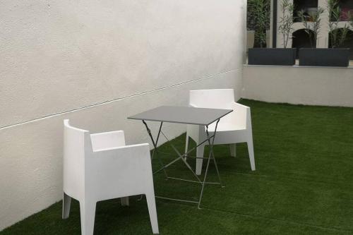 two white chairs and a table in a room with grass at appartement cosy sur Condrieu in Condrieu