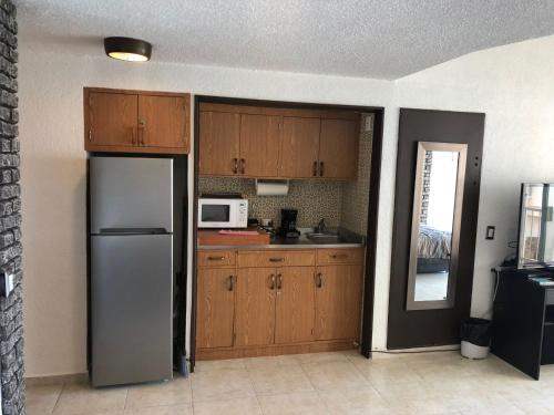 a kitchen with wooden cabinets and a stainless steel refrigerator at SUITE EN TORRES GEMELAS a pie de playa 611 in Acapulco