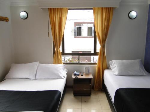 two beds in a small room with a window at Hotel Esmeralda Plaza in Zipaquirá