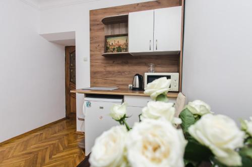 kuchnia z białymi urządzeniami i kwiatami na pierwszym planie w obiekcie Апартаменти на площі Ринок w Lwowie